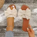 Elegantes sandalias planas crema para mujer con lazo grande y bordes de tachuelas doradas - 36 / Beige