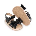 Detailansicht glänzender schwarzer Babysandalen mit Schleife und einer rutschfester Sohle - 11cm / Schwarz