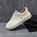 Premium men's off-white leather platform sneakers featuring a retro lace-up casual design. - White