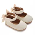 Nahaufnahme von Baby-Prinzessin-Schuhen mit Perlenspitze und eleganten Satinschleifen - Aprikose