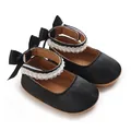 Nahaufnahme schwarzer Satin-Baby-Prinzessinenschuhe mit Perlenspitze und Schleife - Schwarz