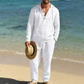 Mann in weißem Leinen-Langarm-Henley-Hemd mit Kapuze und passender Hose am Strand - Weiß