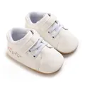 Primer plano de zapatillas blancas para bebé con cordones azules y bordados - Estilo Blanco Rojo