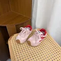 Primer plano de zapatillas retro para niños en rosa y rojo sobre una silla de ratán - 22 (Longitud Interior 14cm) / Rosa