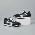 Baskets modernes pour hommes en cuir noir et blanc présentées sur un socle blanc élégant - 38 / Noir