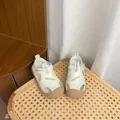 Vue détaillée de sandales crème pour enfants avec semelles souples sur chaise. - Blanc Cassé