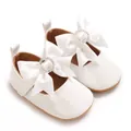 Detail of white baby shoes featuring a large satin bow with sparkling rhinestone circle - White