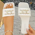Close-up view of elegant white flat slide sandals featuring a metal chain buckle - 35 / White
