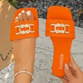 Detailed view of vibrant orange flat sandals featuring a stylish golden chain link buckle - Orange