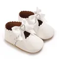 Gros plan sur des chaussures de princesse bébé blanches avec nœud et strass cœur. - Blanc