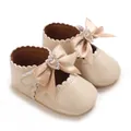 Gros plan de chaussures bébé beiges avec nœuds en satin et boucles en strass en cœur. - Abricot