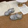 Vista detallada de zapatillas de malla plateadas para niña con flores sobre una alfombra - Plateado