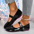 Detailed close-up of shiny black patent leather Mary Jane flats with decorative rose buckle - 36 / Black