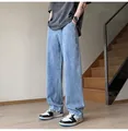 A full-length view of men's loose straight-leg denim jeans in light blue wash for street style - Light Blue
