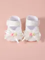 Close-up of white lace baby girl princess shoes with decorative bows and flowers - White