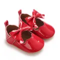 Vue détaillée des chaussures de bébé pour fille en cuir verni rouge vif avec un nœud mignon. - Rouge