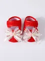 Close-up of red baby girl princess pre-walker shoes featuring a delicate white lace bow. - Red