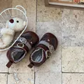 Detailed view of brown mesh toddler shoes with double buckle straps on stone floor. - Brown