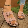 Detailed view of pink suede double-buckle sandals with a thick cork sole on wood - Pink