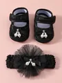 Details der Spitzenstruktur und der Perlenanhänger an Babyschuhen und Stirnband - Schwarz