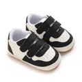 Close-up view of black and white baby walking shoes featuring soft non-slip rubber soles - Black