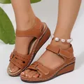 Detalle de sandalias de cuña marrón con calados láser y cierre de velcro ajustable. - Tostado