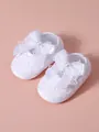 Close-up of white lace baby shoes with decorative bow and pearl detail - White