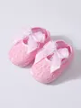 Close-up detail view of pink lace baby shoes with soft soles and white bow decor - Pink
