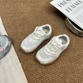 Detail of cream girls' mesh sneakers with pink flower accents on a textured rug. - 34 / Inner Length 21.5cm / Off White