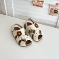 Süße cremefarbene Kindersandalen mit braunen Bären- und Blumenanhängern verziert - Beige