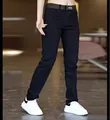 Close-up detail of slim-fit men's black casual jeans styled with a belt and sneakers - 28 / Black