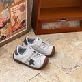 Detailed view of children's grey suede sneakers with star motif and brown rubber soles - Beige