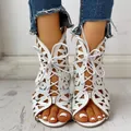Nahaufnahme der weißen flachen Sandalen mit Laser-Schnitt-Muster und Schnürung - Weiß