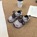 Macrobeeld van roze ademende mesh kinderschoenen met donkere veters op een tapijt. - Roze