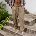 Detail shot of men's loose khaki linen trousers with drawstring waist on stone steps. - Dark Khaki
