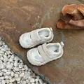 Detalle de los zapatos de bebé crema con malla y velcro sobre una superficie de piedra - 28 / Blanco Roto