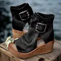Stylish black leather peep-toe wedge booties with decorative buckle on a wooden platform - 35 / Black