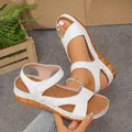 Close-up detail of white women's platform wedge sandals featuring velcro straps and a peep toe - White