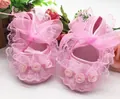 Detailed macro view of pink lace baby walking shoes featuring fabric roses and ribbon bow - Pink