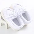 Dettaglio di scarpe in tela bianche per neonati con suola morbida e lacci - Bianco