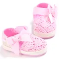 Primer plano de zapatos de bebé de ganchillo rosa con un gran lazo de cinta suave - Rosa