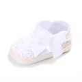 Gros plan sur une chaussure de bébé au crochet blanc avec un grand nœud en satin blanc - Blanc