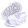 Close-up of cute white baby girl sandals with decorative bow and soft sole. - White