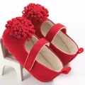 Primer plano de zapatos de princesa para bebé en terciopelo rojo con grandes pompones. - Rojo