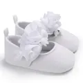 Nahaufnahme weißer Prinzessinnenschuhe für Babys mit zarter Stoffblumendekoration - Weiß
