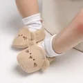 Primo piano dettagliato di graziose scarpine per neonati in maglia beige con gatto - Marrone