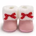 Detail van roze baby-winterschoenen met wit imitatiebont en rode strikken met witte stippen. - Roze