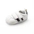 Close-up side view of white baby sneakers featuring two black stripes and velcro straps - White Black
