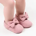 Nahaufnahme der rosa gestrickten Prinzessinnenschuhe für Babys mit einer großen Schleife - Rosa