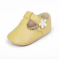 Detail of yellow baby walking shoe featuring a cute white flower embellishment. - Yellow